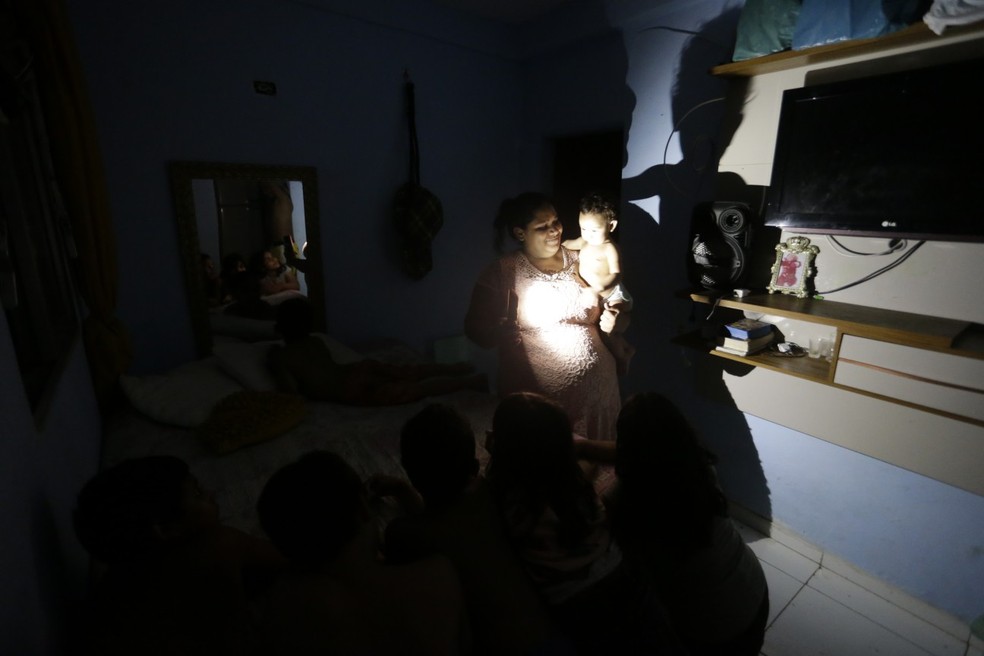 Tamires da Silva, também há oito dias sem luz, passa a noite abanando os filhos. — Foto: Domingos Peixoto / Agência O Globo