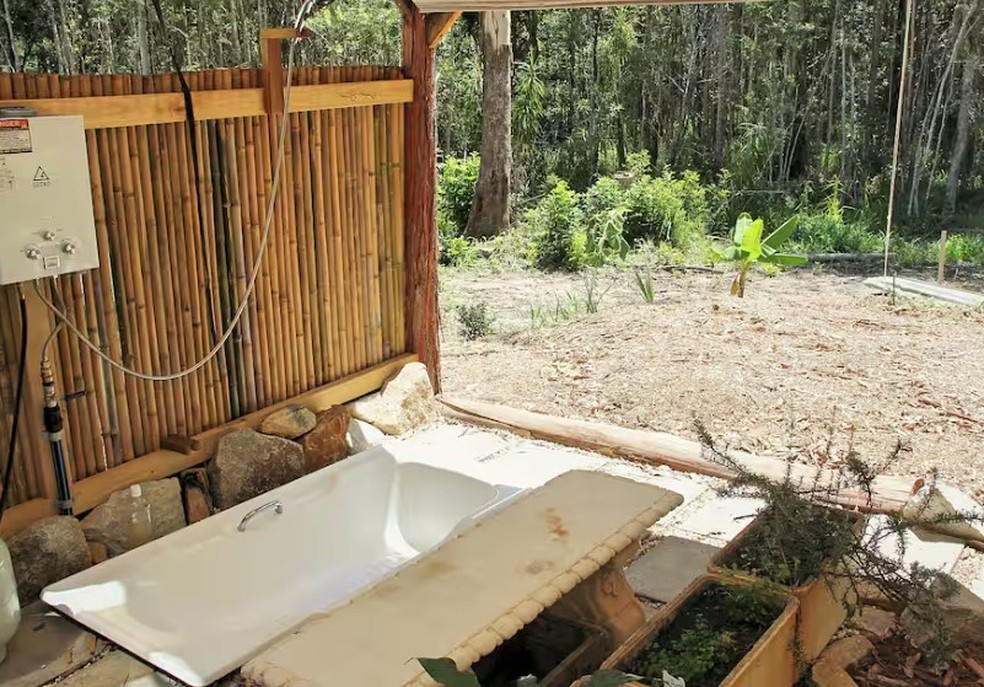 Lucky Duck Bus, em Valla (Austrália), banheira no chão da área externa — Foto: Reprodução / Airbnb
