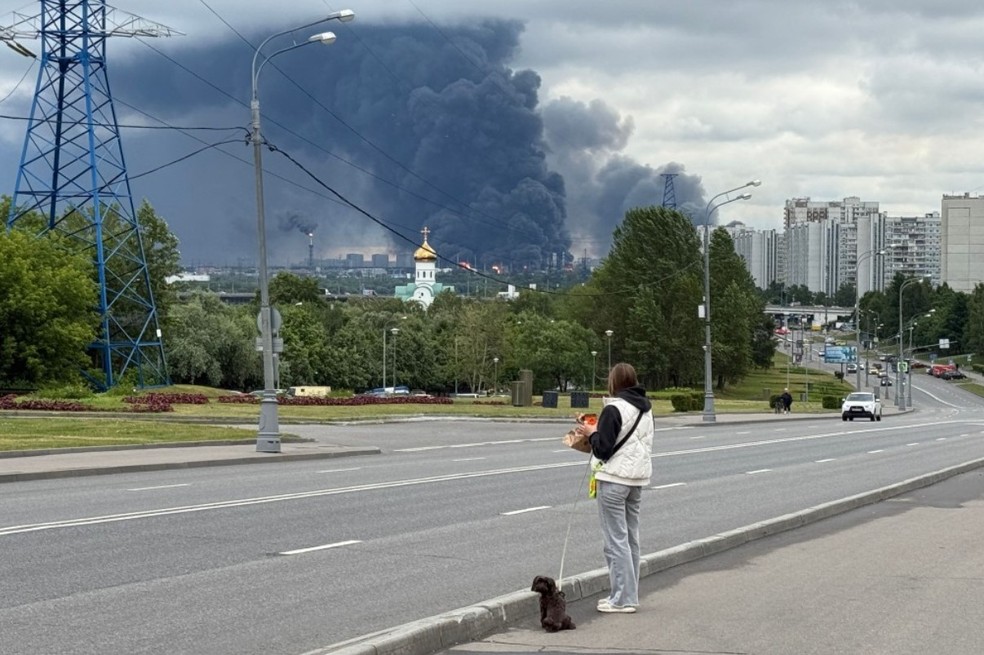 Moradora de Moscou observa imensa coluna de fumaça após ataque ucraniano contra refinaria da Gazprom — Foto: AFP