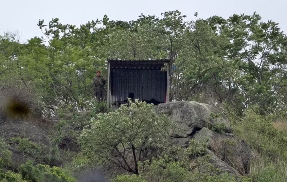 Flagrante: ponto de observação na Serra da Misericórdia, com suspeito, de roupa camuflada, ao lado da estrutura — Foto: Fabiano Rocha / Agência O Globo