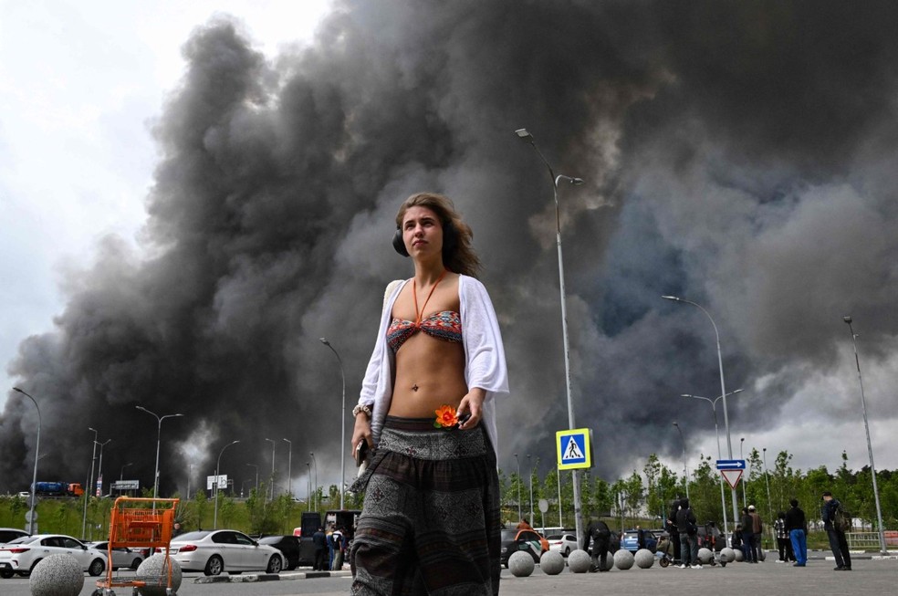 Jovem 'alheia' a explosões em Moscou se destaca diante de imensa coluna de fumaça provocada por ataque ucraniano — Foto: AFP
