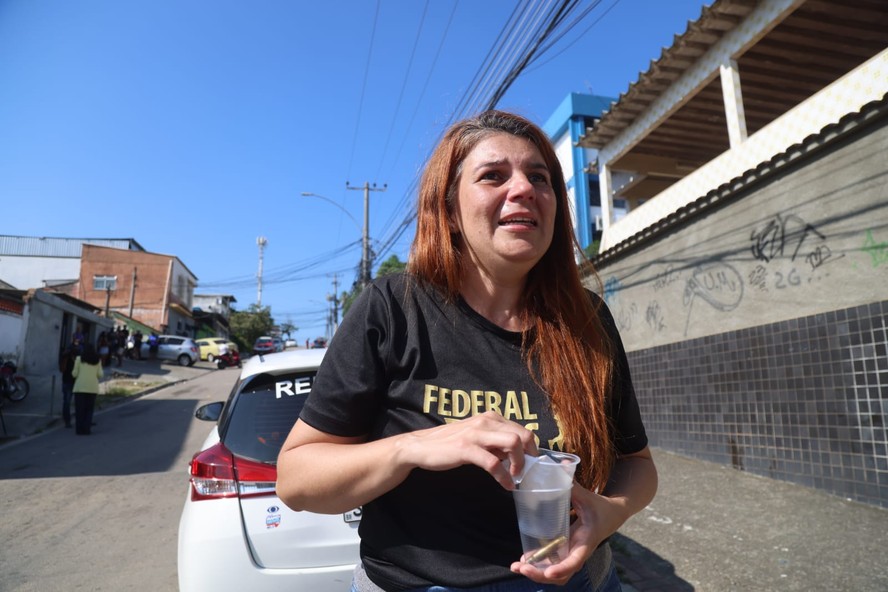 Tais Oliveira segura as cápsulas que encontrou no local onde o irmão foi morto