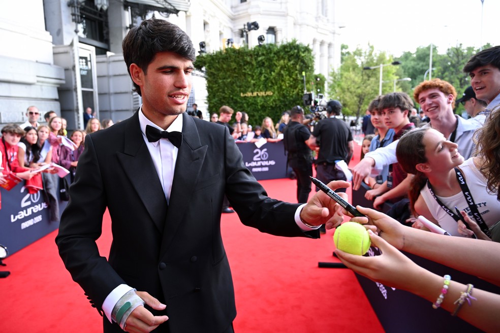 Alcaraz autografa bola de tênis no tapete vermelho do Prêmio Laureus 2026 — Foto: Borja B. Hojas/Divugação Laureus