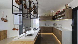 Cozinha com ilha, iluminação embutida, spots por cima da bancada e panelas suspensas para complementar estilo  — Foto: Leo Martins/Agência O Globo
