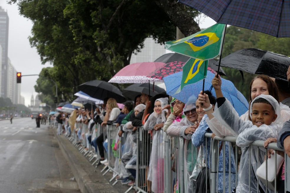 Com capas e bandeiras do Brasil, público aguarda início do desfile na Avenida Presidente Vargas — Foto: Márcia Foletto / Agência O Globo
