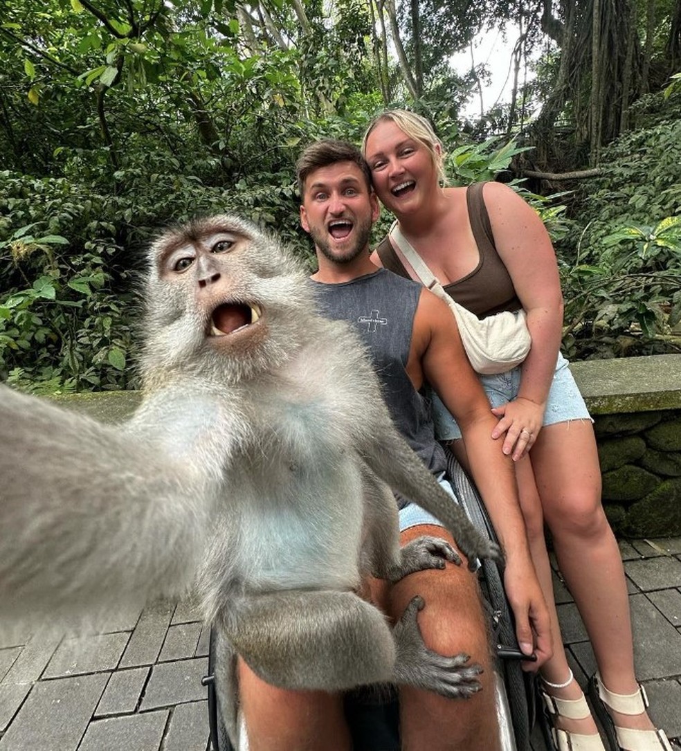 Macaco faz selfie com casal britânico em reserva natural de Bali — Foto: Reprodução/Instagram(mrschlodennis)