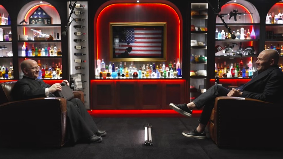 Cenário do "Shawn Ryan Show", onde o padre Chad Ripperger foi entrevistado, é decorado com bebidas e armas — Foto: Reprodução/Youtube