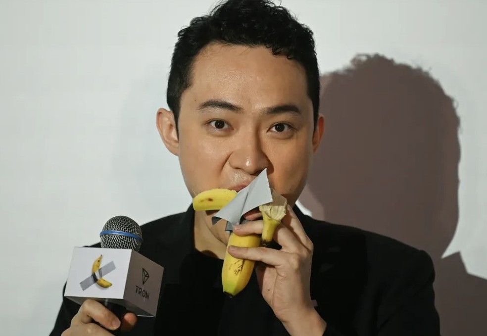 Justin Sun come a banana de famosa obra de arte após pagar uma fortuna por ela — Foto: AFP