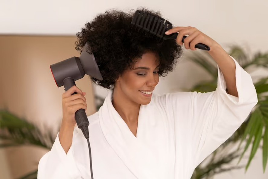 Cabeleireiro seca e modela o cabelo com um secador de cabelo no