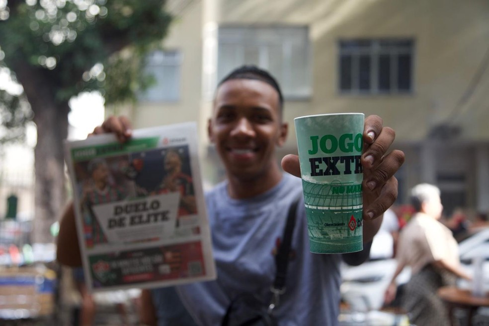 O autônomo Wallace Da Silva, de 22 anos com o jornal e copo do Jogo EXTRA no Maraca — Foto: Júlia Aguiar/ O GLOBO