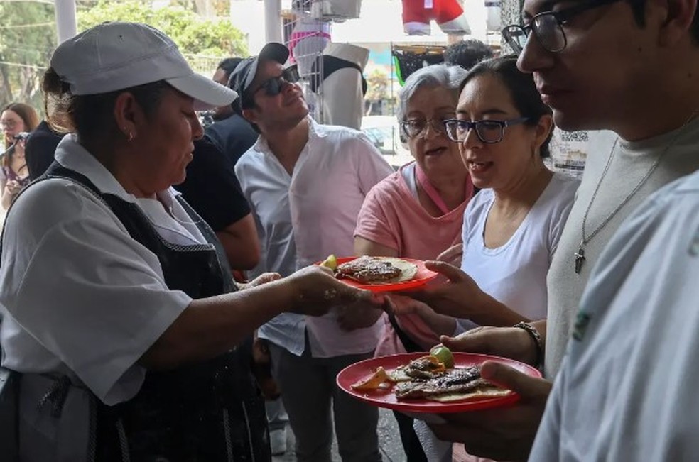 Clientes da Taquería El Califa de León recebem os seus pedidos — Foto: AFP