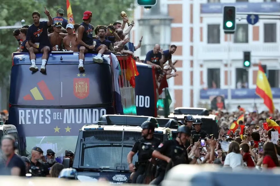 Os jogadores da Espanha desfilam em um ônibus aberto pelas ruas de Madri, em 20 de julho de 2026, um dia após a seleção conquistar seu segundo título da Copa do Mundo com a vitória por 1 a 0 sobre a Argentina. Os campeões mundiais retornaram à capital espanhola para uma recepção de heróis, onde cerca de um milhão de torcedores eram esperados para saudá-los após uma noite de intensas comemorações por todo o país — Foto: Thomas COEX / AFP