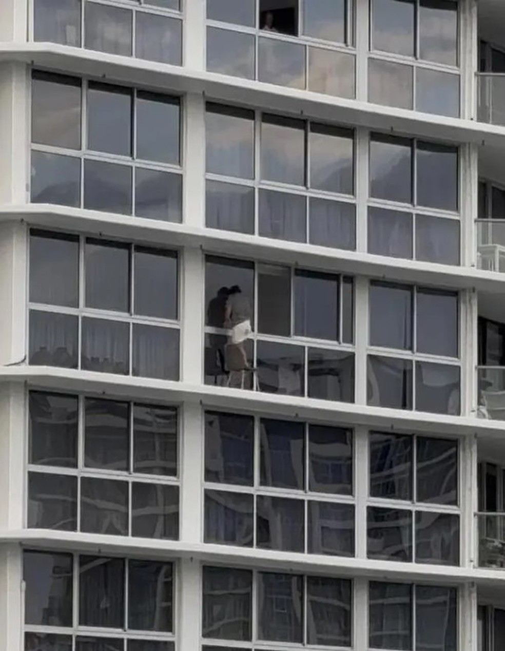 Mulher se equilibra em cadeira em fachada de apartamento no 16º andar de prédio de Gold Coast (Austrália) — Foto: Reprodução