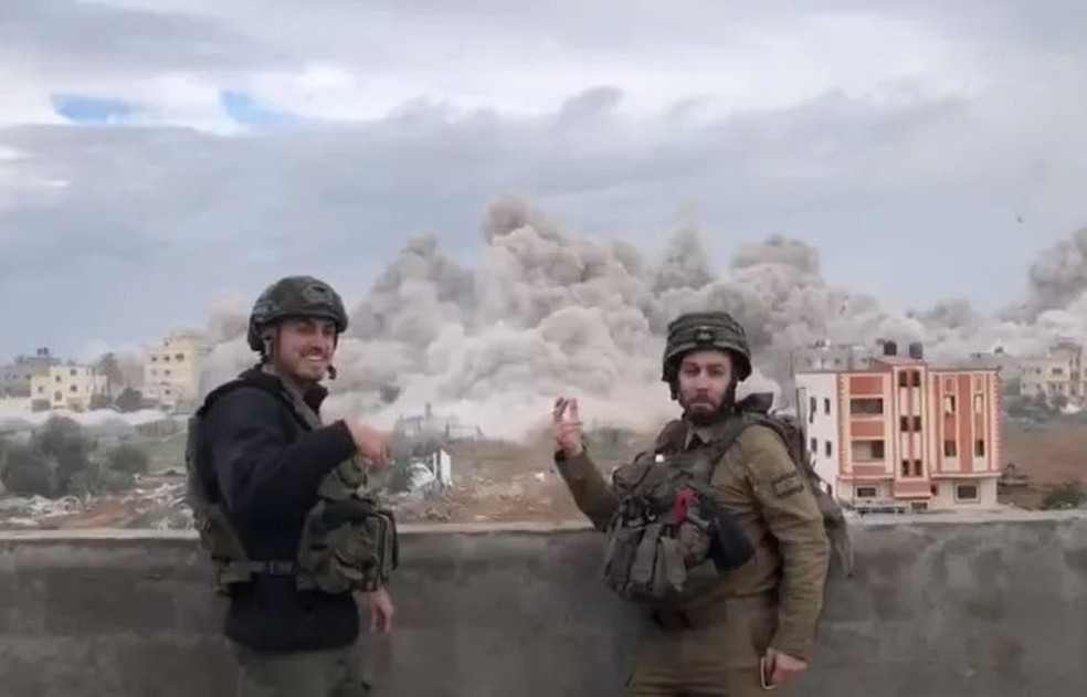 Soldados de Israel sorriem com explos&otilde;es em Gaza ao fundo &mdash; Foto: Reprodu&ccedil;&atilde;o/Facebook