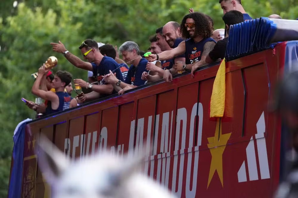 O defensor Marc Cucurella dispara uma pistola de água enquanto os jogadores da Espanha desfilam em um ônibus aberto pelas ruas de Madri, em 20 de julho de 2026, um dia após a seleção conquistar seu segundo título da Copa do Mundo com a vitória por 1 a 0 sobre a Argentina. Os campeões mundiais retornaram à capital espanhola para uma recepção de heróis, onde cerca de um milhão de torcedores eram esperados para saudá-los após uma noite de intensas comemorações por todo o país — Foto: Cesar MANSO / AFP