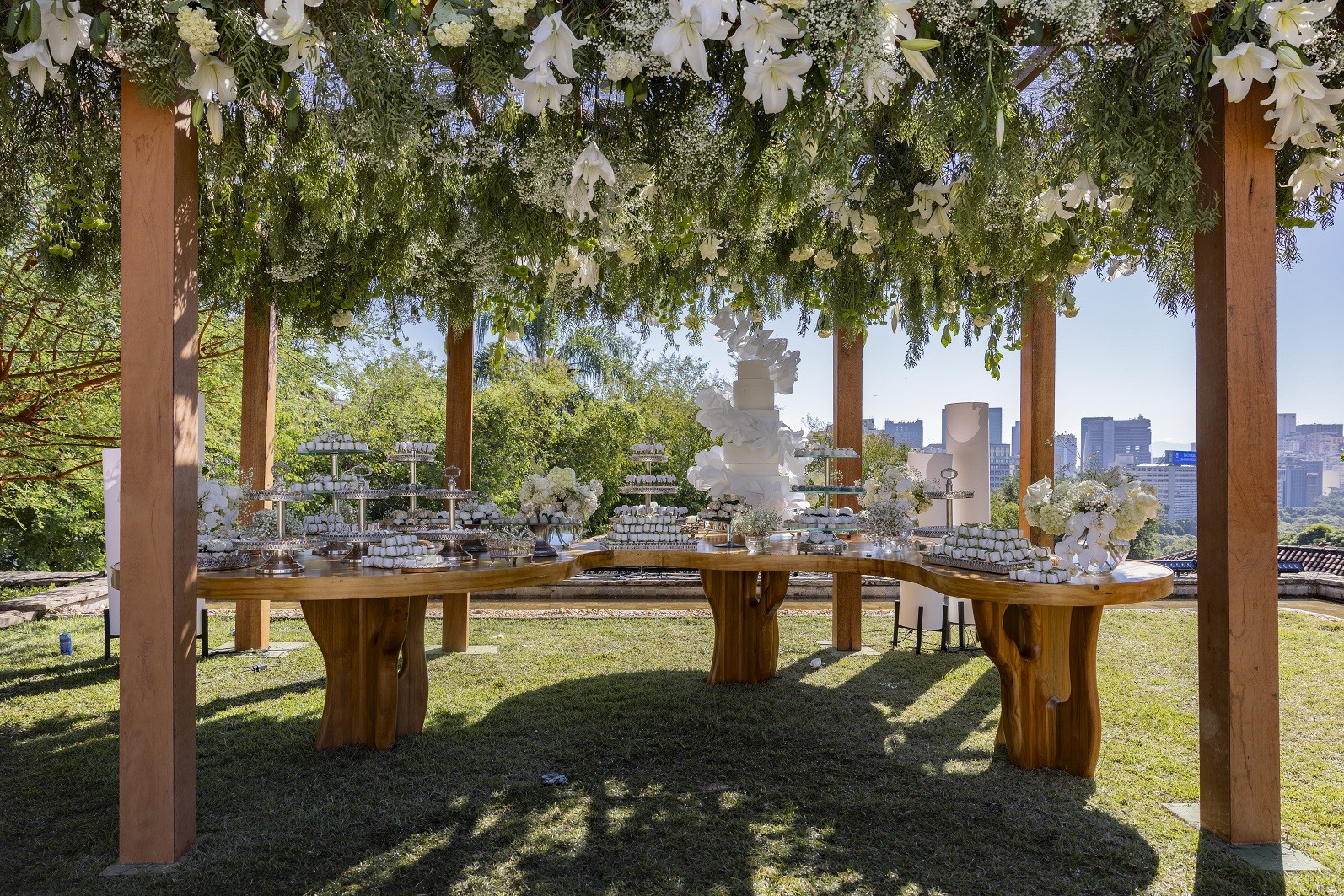 Vista geral da mesa de doces com arranjos florais suspensos e o Rio ao fundo, no casamento de Maria de Fátima e Afonso no remake de 'Vale tudo' — Foto: Fábio Rocha/Globo/divulgação — Foto: Fábio Rocha/Globo/divulgação