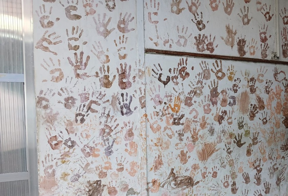 Parede com mãos gravadas de profissionais e alunos do CAp UFRJ, no pátio da instituição — Foto: Walter Farias