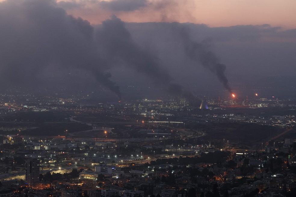 Colunas de fuma&ccedil;a em Haifa, no norte de Israel, atingida por m&iacute;sseis iranianos &mdash; Foto: Ahmad GHARABLI / AFP